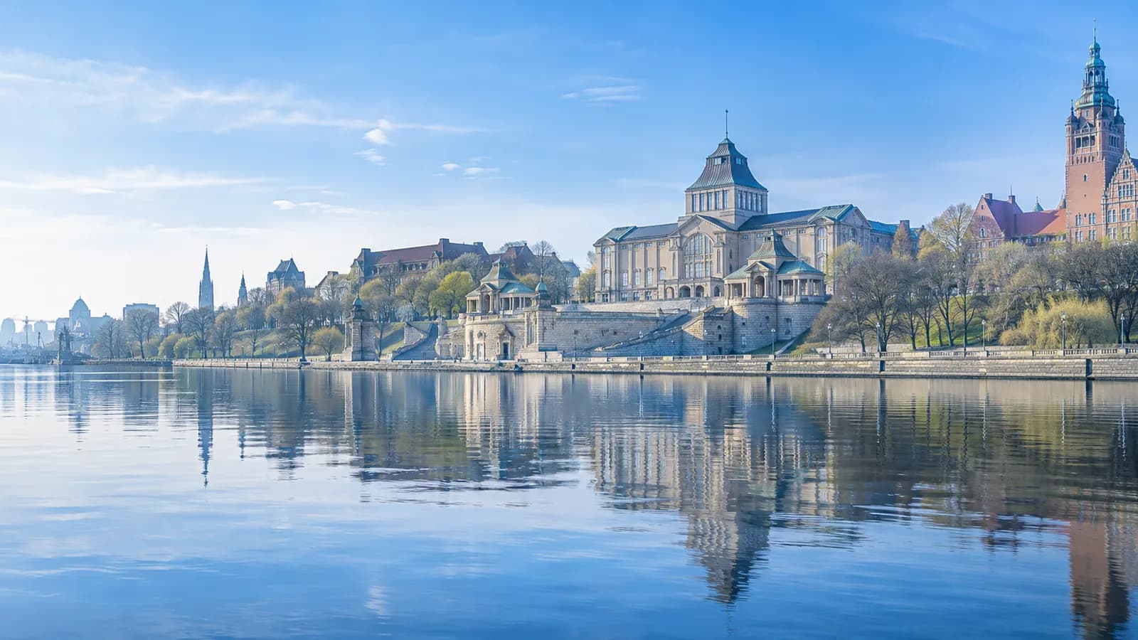 Wały Chrobrego w Szczecinie w jasny poranek, widok znad Odry na Muzeum Narodowe i gmach urzędu wojewódzkiego odbite w spokojnej wodzie